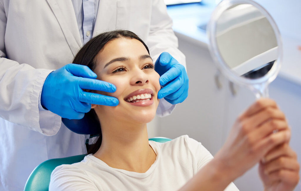 Woman, dentist and happy with mirror for dental surgery in clinic for teeth whitening and treatment with doctor. Female patient, satisfied and smile on consultation for canal procedure and oral care.