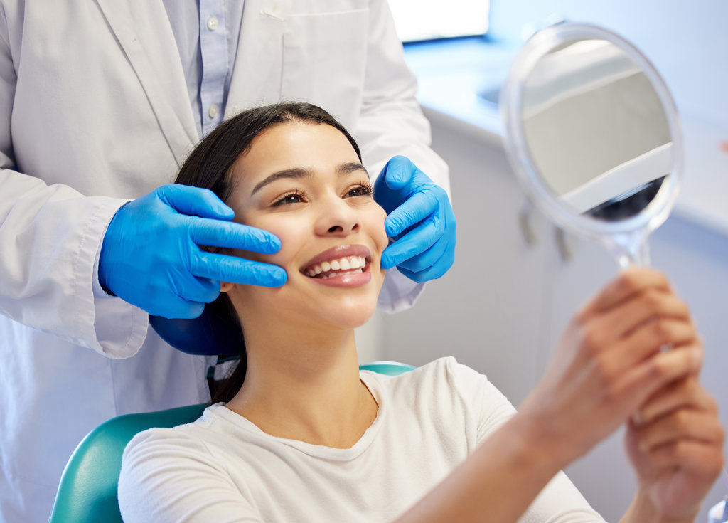 Woman, dentist and happy with mirror for dental surgery in clinic for teeth whitening and treatment with doctor. Female patient, satisfied and smile on consultation for canal procedure and oral care.