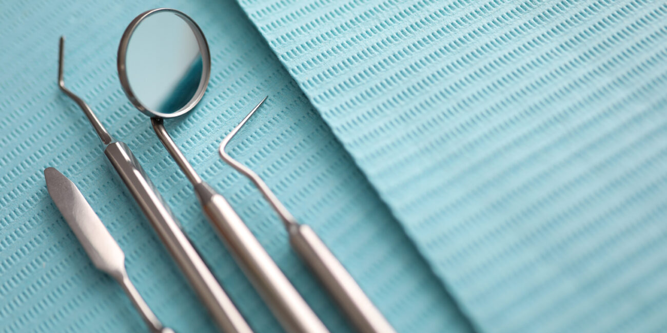 Pile of dentist tools lying at green tissue ready to be used close-up